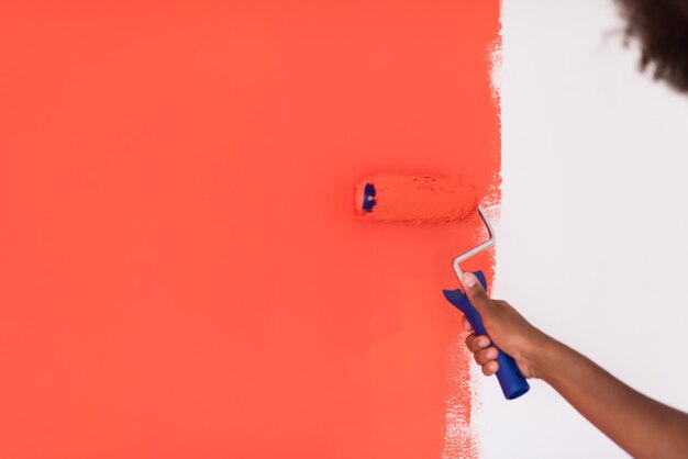 Photo portrait d'une belle jeune femme afro-américaine peignant un mur dans son nouvel appartement