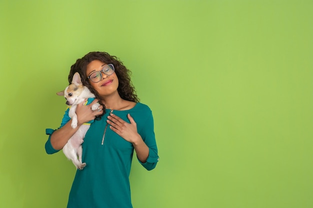 Portrait de belle jeune femme afro-américaine avec petit chien sur fond vert studio