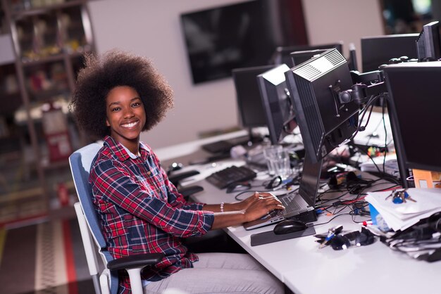 portrait d'une belle jeune femme afro-américaine réussie qui aime passer un moment de qualité et joyeux tout en travaillant dans un grand bureau moderne