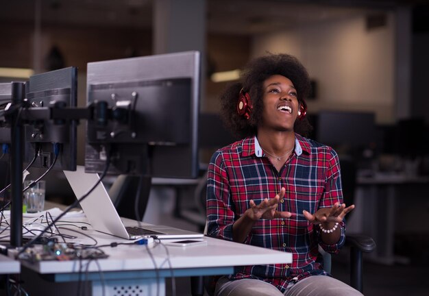 portrait d'une belle jeune femme afro-américaine réussie qui aime passer un moment de qualité et joyeux tout en travaillant dans un grand bureau moderne