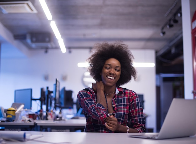 portrait d'une belle jeune femme afro-américaine réussie qui aime passer un moment de qualité et joyeux tout en travaillant dans un grand bureau moderne