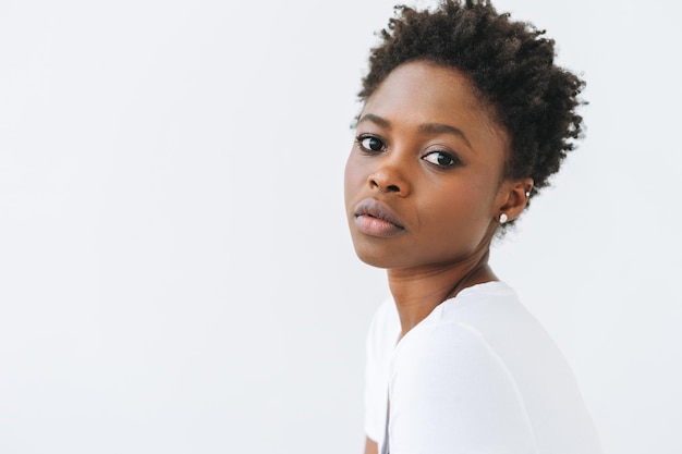 Portrait de la belle jeune femme afro-américaine en t-shirt blanc isolé sur fond blanc