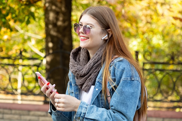 Portrait de la belle jeune femme à l'aide de son téléphone portable dans le parc