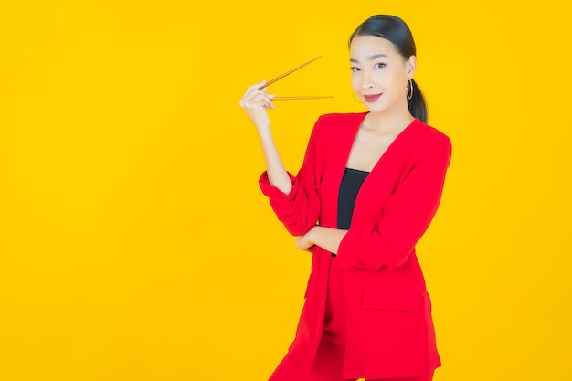 Portrait belle jeune femme asiatique avec des baguettes sur jaune