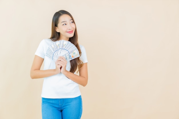 Portrait belle jeune femme asiatique avec beaucoup d'argent et d'argent sur beige