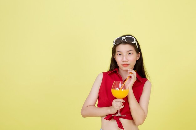 Portrait d'une belle jeune femme asiatique buvant du jus d'orange