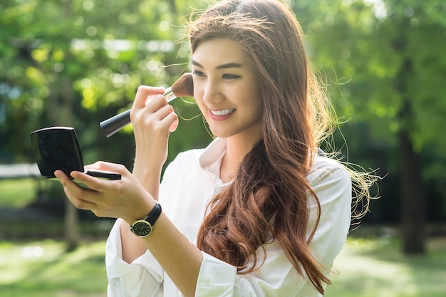 Portrait de la belle jeune femme asiatique composent son visage dans le parc,