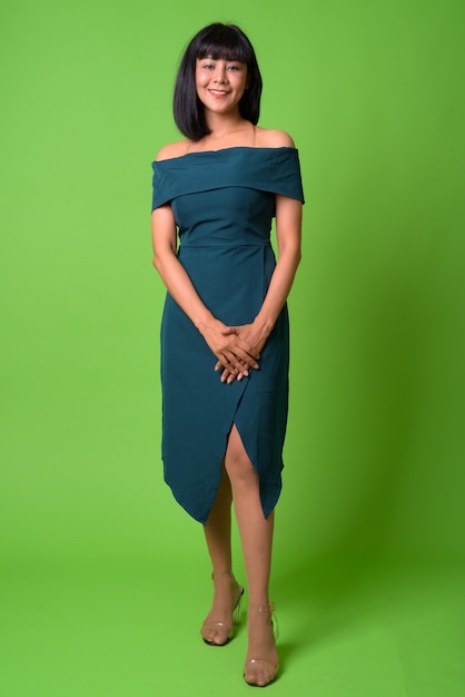 Portrait de la belle jeune femme asiatique contre le mur vert