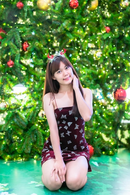 Portrait belle jeune femme asiatique costume de robe rouge et décoration de colis de photo de voeux de Noël sur fond de bokeh circulaire léger de sapin de Noël Décoration pendant Noël et le Nouvel An