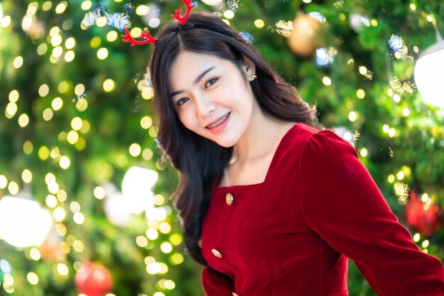 Portrait belle jeune femme asiatique costume de robe rouge et décoration de colis photo de voeux de Noël sur fond de bokeh circulaire lumière arbre de Noël Décoration pendant Noël et nouvel an.