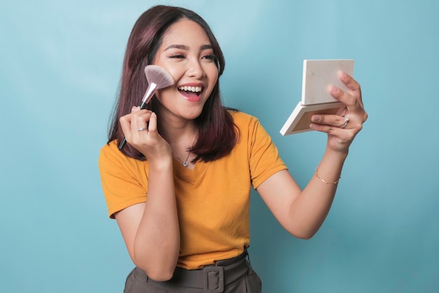 Portrait d'une belle jeune femme asiatique faisant son maquillage