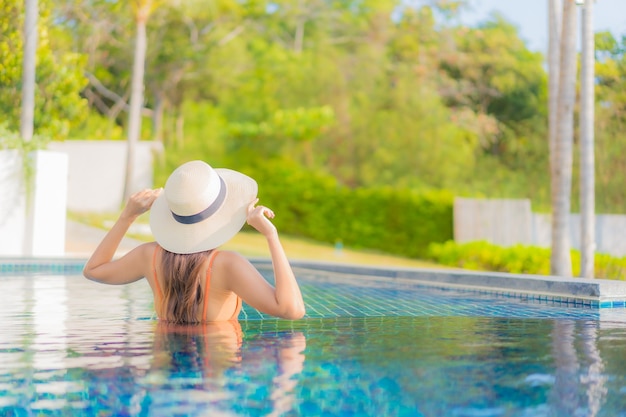 Portrait belle jeune femme asiatique se détendre sourire loisirs autour de la piscine extérieure dans la station de l'hôtel en vacances de voyage