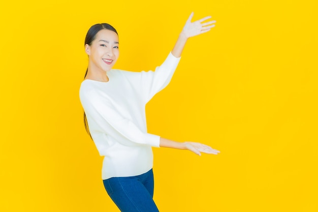 Portrait belle jeune femme asiatique sourire avec action sur jaune