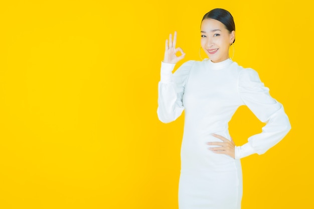 Portrait belle jeune femme asiatique sourire avec action sur jaune