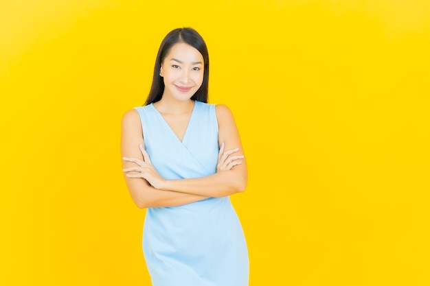 Portrait belle jeune femme asiatique sourire avec action sur le mur de couleur jaune