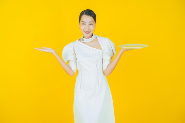 Portrait belle jeune femme asiatique sourire avec assiette vide sur fond de couleur