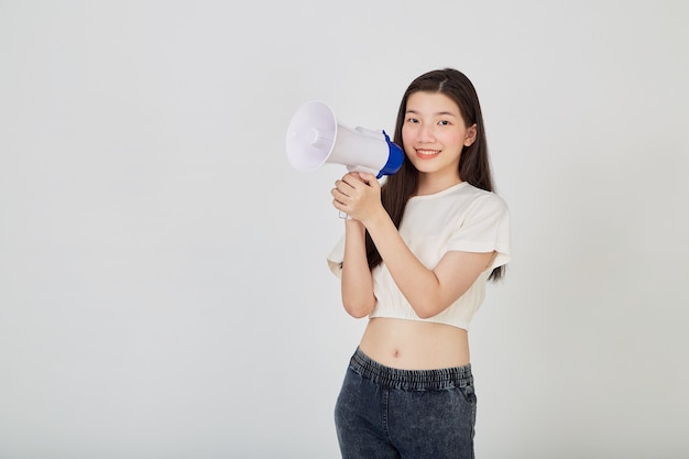 Portrait belle jeune femme asiatique sourire avec mégaphone faisant une annonce en studio isolé