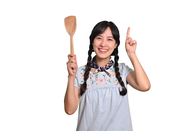 Portrait de la belle jeune femme asiatique sourire en robe denim avec spatule sur fond blanc