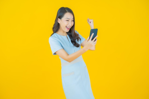 Portrait belle jeune femme asiatique sourire avec téléphone mobile intelligent sur fond de couleur