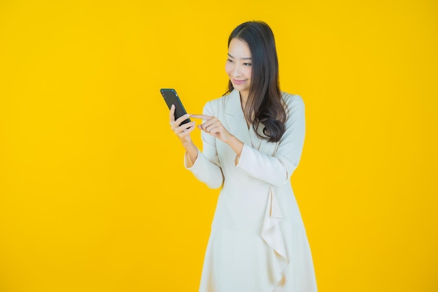 Portrait belle jeune femme asiatique sourire avec téléphone mobile intelligent sur fond de couleur