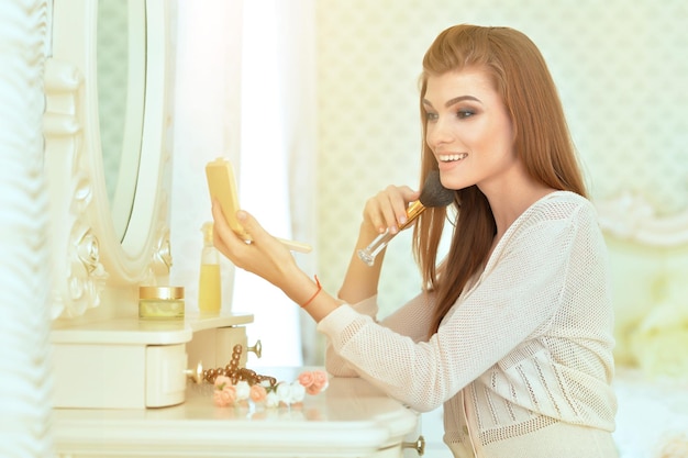 Portrait d'une belle jeune femme assise près d'une coiffeuse à la maison