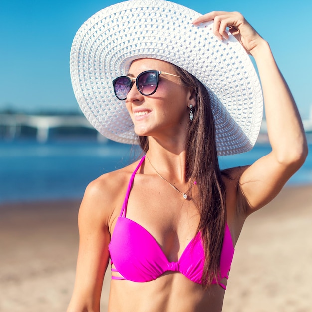 Portrait de la belle jeune femme au chapeau posant en bikini sur la plage