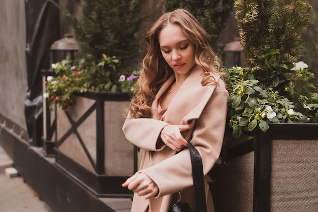 Portrait d'une belle jeune femme aux cheveux longs et au manteau confortable se promène dans la ville