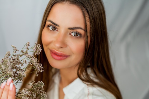 Portrait de la belle jeune femme aux cheveux longs sur fond blanc avec des fleurs séchées Printemps