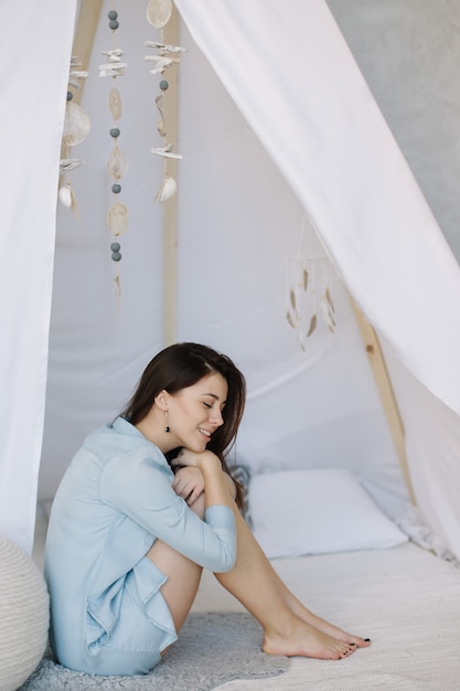 Portrait d'une belle jeune femme aux cheveux noirs au lit le matin à la maison