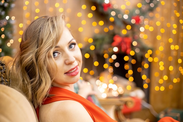 portrait d'une belle jeune femme blonde assise dans une salle décorée pour la célébration du nouvel an. mise au point sélective, flou artistique