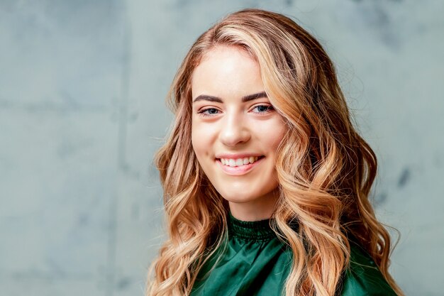 Portrait de la belle jeune femme blonde caucasienne souriante avec une coiffure et un maquillage bouclés parfaits