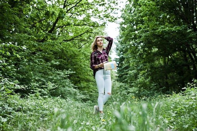 Portrait d'une belle jeune femme blonde en chemise tartan tenant une carte dans la forêt