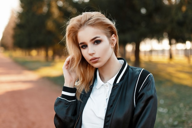 Portrait d'une belle jeune femme blonde dans des vêtements à la mode dans le parc