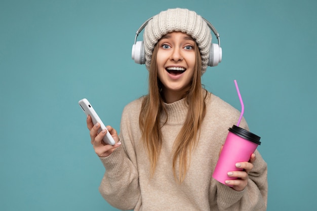 Portrait d'une belle jeune femme blonde heureuse et positive avec des émotions sincères portant un pull beige