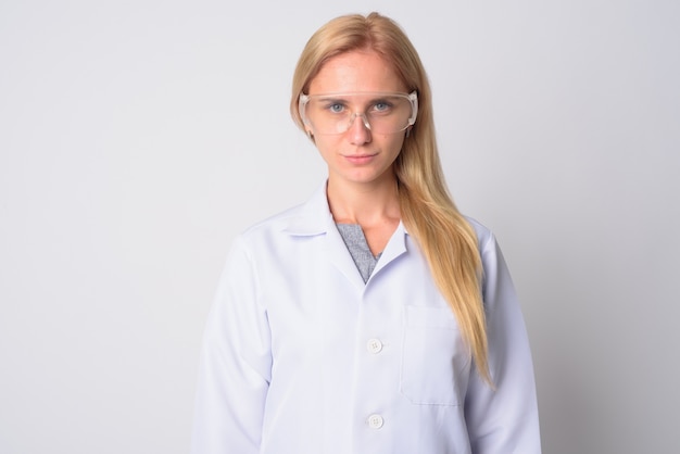 Portrait de la belle jeune femme blonde médecin en tant que scientifique portant des lunettes de protection sur blanc