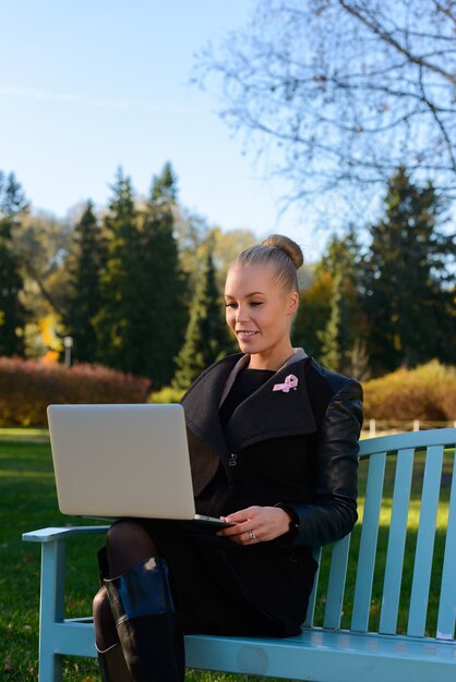 Portrait de la belle jeune femme blonde avec ruban rose pour symbole de la sensibilisation au cancer du sein dans le parc