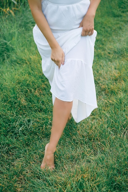 Photo portrait d'une belle jeune femme bouclée aux cheveux noirs de 30 ans dans une robe d'été blanche dans un champ d'été au coucher du soleil