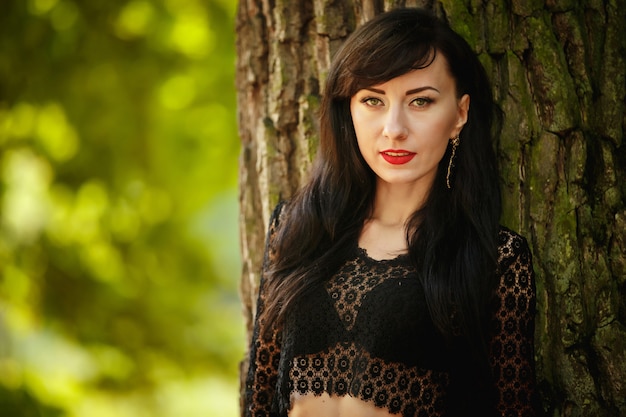 Portrait d'une belle jeune femme brune sur fond d'écorce d'arbre