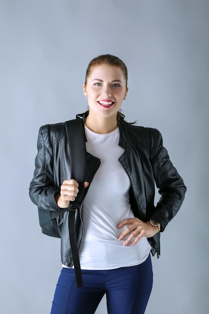 Portrait de la belle jeune femme brune en veste noire élégante sur gris