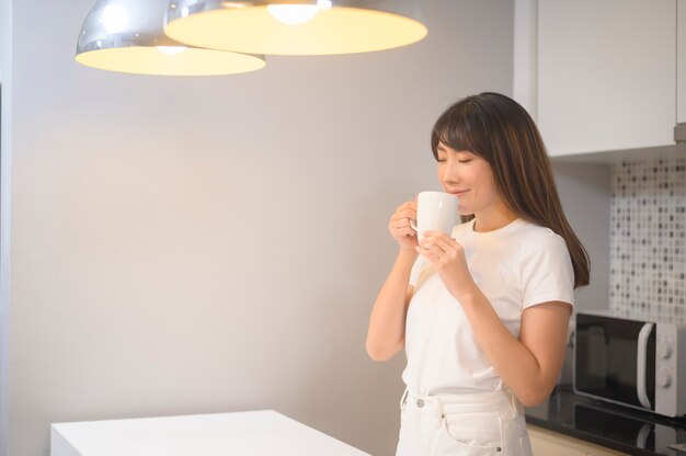 Un portrait de belle jeune femme buvant un verre d'eau dans la cuisine