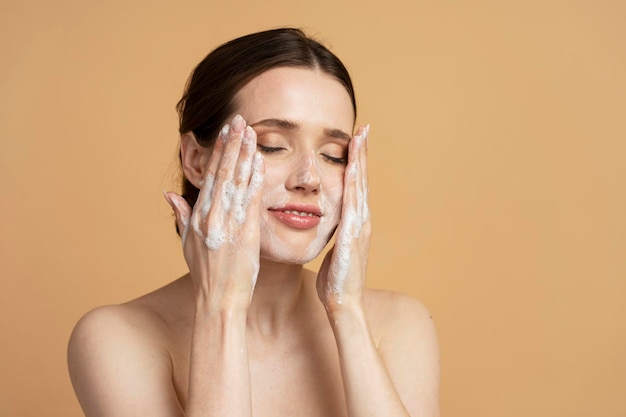 Portrait d'une belle jeune femme caucasienne confiante nettoyant la mousse de savon ou le démaquillant