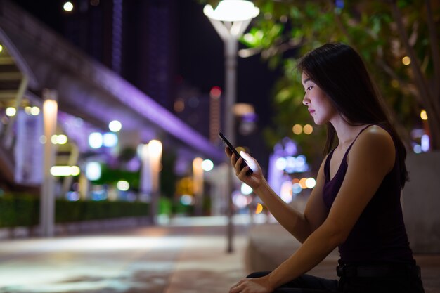 Portrait de la belle jeune femme chinoise à l'extérieur pendant la nuit