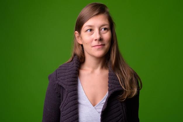 Portrait de la belle jeune femme contre le mur vert