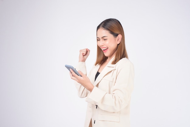 Portrait de belle jeune femme en costume à l'aide de téléphone intelligent sur fond blanc