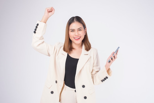 Portrait de belle jeune femme en costume à l'aide de téléphone intelligent sur fond blanc