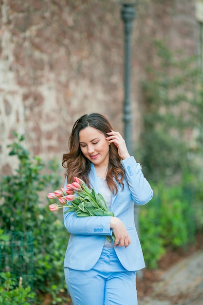 Portrait d'une belle jeune femme en costume bleu avec un bouquet de tulipes