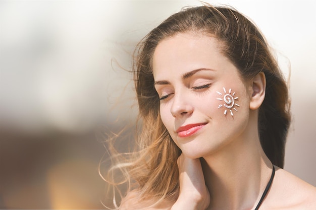 Portrait d'une belle jeune femme avec de la crème solaire sur la joue