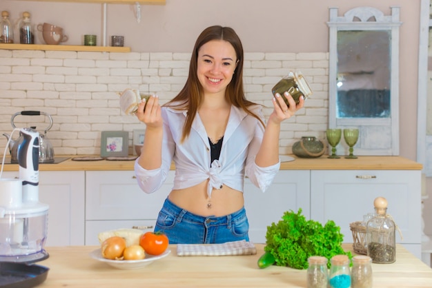 Portrait de la belle jeune femme cuisine dans la cuisine. Jeune femme cuisine. Alimentation saine - salade de légumes.