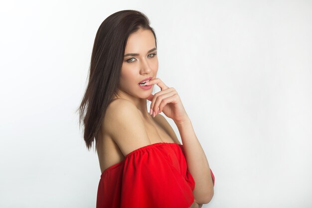 Portrait d'une belle jeune femme dans une robe rouge sur fond blanc