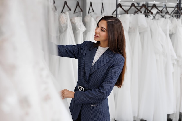 Photo portrait d'une belle jeune femme dans un salon de mariage elle choisit une belle robe de mariée blanche.